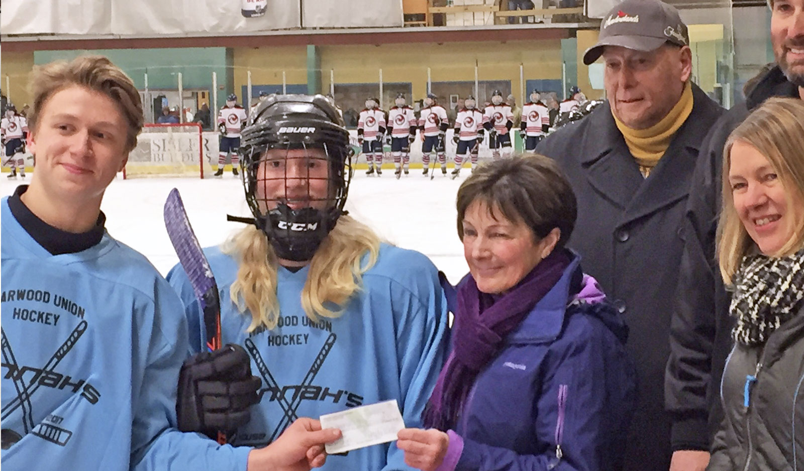 Harwood Hockey team wearing Hannah's House jerseys and donating check to Hannah's house